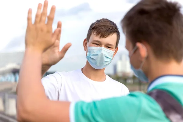 Gençlerin iki arkadaşı şehirde buluşuyor. Birbirlerine temas etmeden selamlaşıyorlar. Yüzlerinde tıbbi maskeler var. 2020 'deki yeni normal..