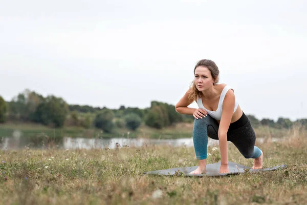 Nehir kenarında, ormanın arka planına karşı spor yapan genç bir kadın. Nehir kenarında spor yapan genç bir kadın ormanın arka planında spor yapıyor..