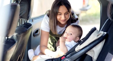 Little baby in a car seat in the car. Shot straight. The kid looks at the camera. clipart