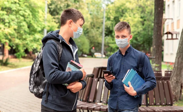 Δύο φίλοι από το σχολείο, έφηβα αγόρια είναι στην αυλή του σχολείου φορώντας ιατρικές μάσκες στα πρόσωπά τους.. — Φωτογραφία Αρχείου