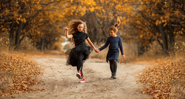 Dos adolescentes caminan a lo largo de un camino forestal en el cálido otoño. — Foto de Stock
