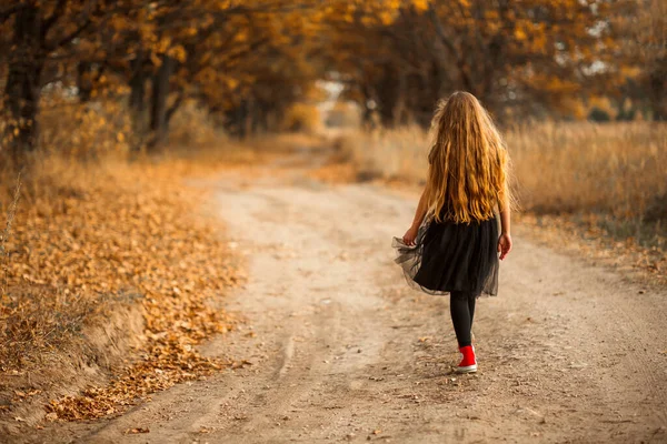 Una adolescente con el pelo largo y rizado está caminando a lo largo de un sendero forestal. — Foto de Stock