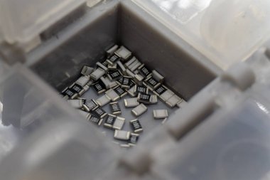 Gri dağınık mikroskobik SMT yüzey montaj çipi rezistörleri gri depolama konteynırında sıralandı