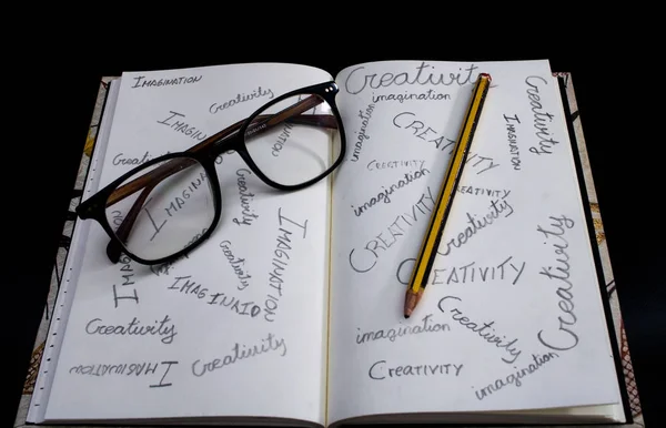 创造性和想象力写在笔记本上，上面有眼镜和铅笔 — 图库照片