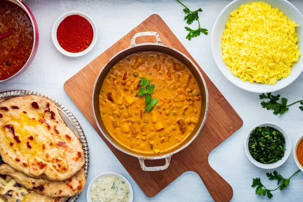 Indiai ételek: Curry Pot tele borsóval és burgonyával rizses tálkával, Dal Pot, Naan Kenyér és fűszerek. — Stock Fotó