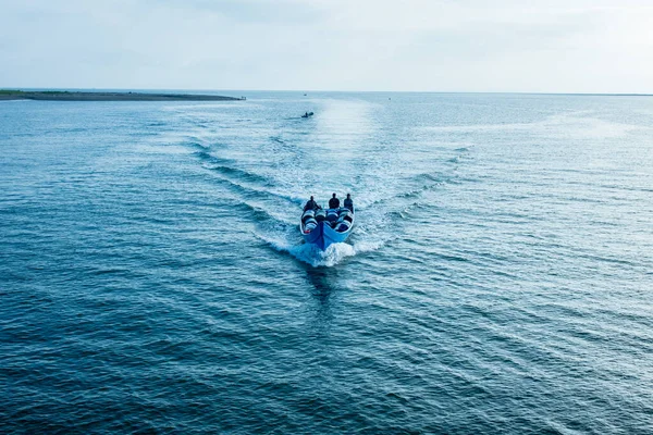 Muchos hombres en el barco azul de la velocidad llenan con la mercadería que cruza en la bahía — Foto de Stock