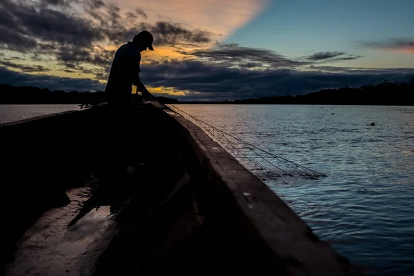 Hombre pescando con una red de pesca al atardecer con puesta de sol en el fondo en el río Beni — Foto de Stock
