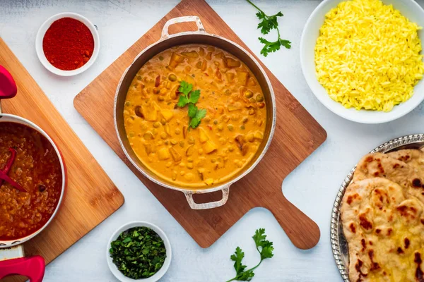 Indiai ételek: Curry Pot tele borsóval és burgonyával rizses tálkával, Dal Pot, Naan Kenyér és fűszerek. — Stock Fotó