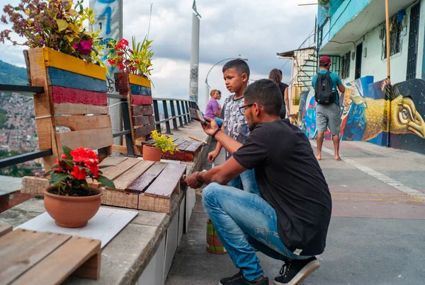 Medellin, antioquia / kolumbien - 11. august 2019: kleiner junge beim bemalen von bänken in den farben der kolumbianischen fahne mit seinem vater in commune 13 — Stockfoto