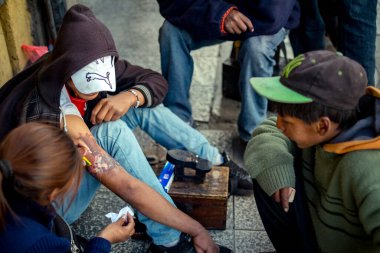 La Paz / Bolivya - 25 Kasım 2014: Genç Esmer Kadın Hidrojen Peroksit ile Genç Yerli Ayakkabı Parlatıcı Çocuğun Kolundaki Yaraları İyileştiriyor