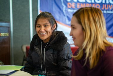 La Paz / Bolivya - 17 Aralık 2014: Yerli Özellikli Genç Kadın Sarışın Bir Kadının Yanında Oturuyor ve Gülümsüyor