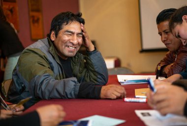 La Paz / Bolivya - 17 Aralık 2014: Yerli Özellikli Adam, Kırmızı Masa Örtülü Arkadaş grubuyla Güler