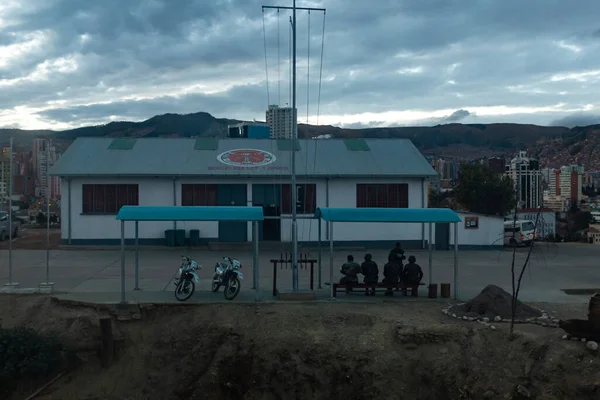 拉巴斯 玻利维亚 2015年8月11日 有一个加胺屋顶和混凝土庭院的房子 一些身着迷彩服的男子在一些摩托车附近休息 — 图库照片