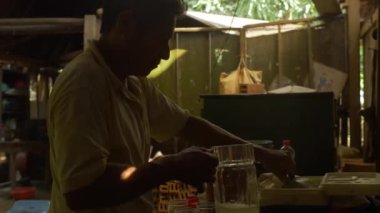 Riberalta, Beni / Bolivya - 28 Ekim 2015: Man bir evin içinde cam kavanozda metal kavanozla soğutucudan su servis ediyor