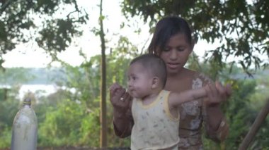 Riberalta, Beni / Bolivya - 18 Ekim 2015: Bolivya Amazon 'unda Yerli Özellikli Esmer Kız Bir Bebek Tutuyor