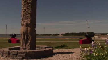 Anticosti Adası, Quebec / Kanada - 8 Ağustos 2008: Denize Yakın Kare Köy Hayvanlarını temsil eden bir Geyik Heykeli, Uzaktan Dalgalanan Kara Toplar ve Bayraklar 
