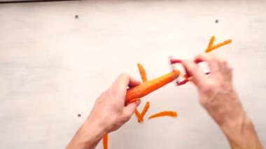 Beyaz adamın eli, arka planda sebze soyucuyla havuç soyuyordu.