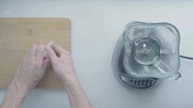 Medellin, Antioquia / Kolombiya - 9 Ocak 2020: Beyaz adamın eli Beyaz Masa 'daki bir kesme tahtasında biraz sarımsak soyuyor ve yanında da blender