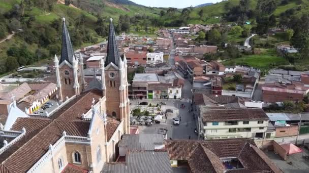 大きな大聖堂のある典型的なアンティオキア村牧草地や山の緑の丘に囲まれてBelmira Antioquia コロンビアの空中ビュー — ストック動画