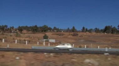 Teotihuacan Tapınağı 'na giden asfalt yol. Dağlar, ağaçlar ve kuru arazi manzaralı.