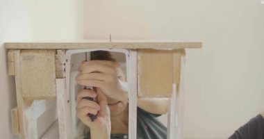 Genç Sarışın Kafkasyalı ve Erkek Çöreği Masa Altında Oturuyor. Ahşap paletlerle elle düzüşüyor. 