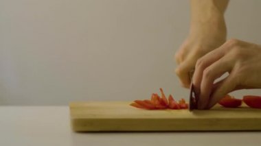 Beyaz arka planda kesim tahtasındaki mutfak bıçağıyla beyaz adamın eli biber (Aji) kesiyor. 