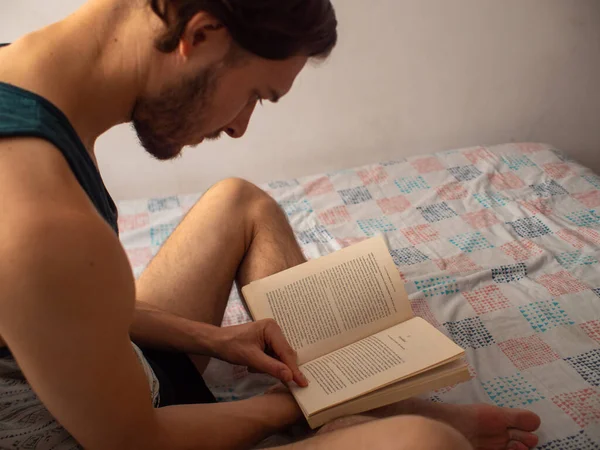 Joven Caucásico Muy Concentrado Lee Gran Libro Sentado Una Cama — Foto de Stock