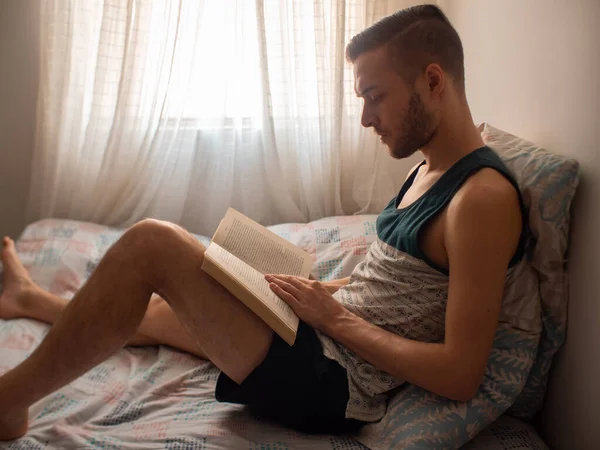 Молодой Кавказский Человек Читает Большую Книгу Сидя Белой Стене Листовой — стоковое фото