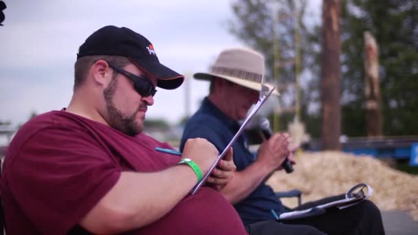 加拿大魁北克Senneterre 2011年7月12日 肥胖男子在表格上写成绩 旁边是一个对着麦克风讲话的男子 — 图库视频影像