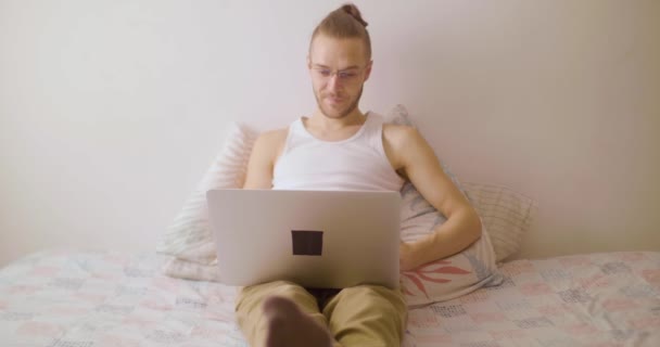 メガネをかけた白人ブロンドの男がノートパソコンで映画を見ている — ストック動画
