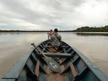 Puerto Maldonado, Madre de Dios / Peru - February 3 2013: Man Rowing a Canoe with other People in the Madre de Dios River in the Peruvian Amazon clipart