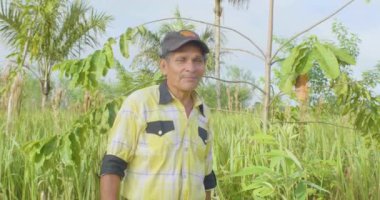 Riberalta, Beni / Bolivya - 7 Nisan 2017: Sarı Gömlekli İspanyol Yetişkin Erkek Yeşil Tarım Arazisi Kameraya Şarkı Söylüyor