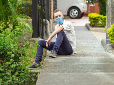 Kafkasyalı Genç Adam Mavi Işık Çiçekleriyle Kaldırımda Oturuyor El Sanatları Maskesi Kameraya Bakıyor