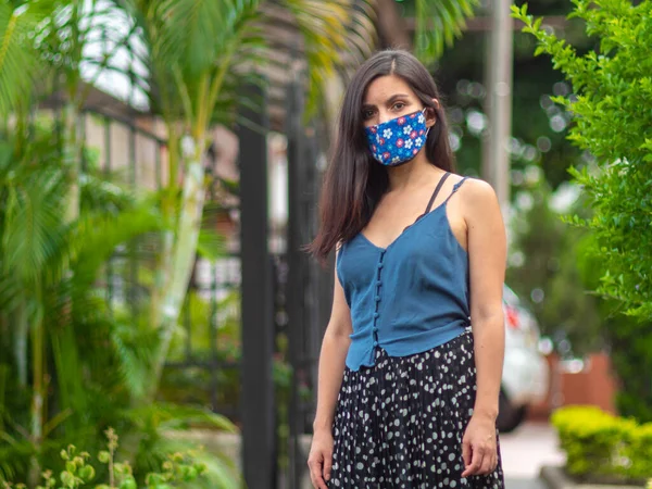 西班牙裔年轻女人带着蓝色花手工操作的面罩看着相机 — 图库照片