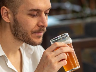 Beyaz tişörtlü beyaz adam Büyük Camlı Kırmızı El Sanatları Birası İçiyor