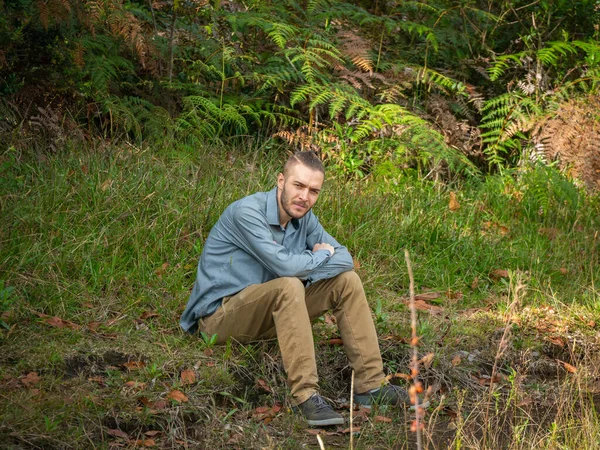 Caucasian Blond Man is Sitting in the Ground in the Middle of the Nature