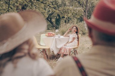 Bahçede oturan dedesi ile yaşlı büyükanne geri görünümü. Mutlu aşk çift dedesi. Arka planda torunu masada oturuyor ve elini sallayarak