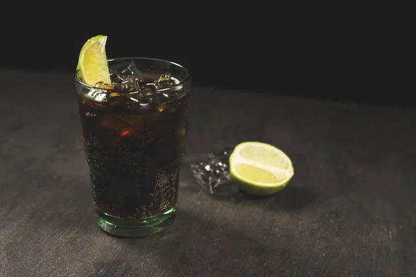 drink with lemon and ice in glass on black table