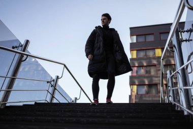 Binaların yakınındaki merdivenlerden çıkan güzel adam modelinin portresi. Sokak şehir tarzı