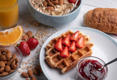 Yulaf lapası ve beyaz arka planda meyveli ve fındıklı Belçika waffle 'ı. Günaydın enfes müsli, kruvasan. Yemek takımı..