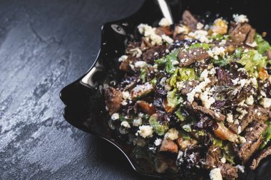 Sebze, et ve feta ile nefis taze salata siyah bir tabakta arka planda.