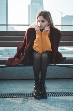 Güzel genç bir sarışın kız şehrin sokaklarında yürüyor, gülümsüyor, paltosunu sallıyor. O, turuncu bir kazak ve siyah bir tayt giyiyor, kırmızı bir ceket. Sıradan bir sokak tarzı. Mutluluk duygusu