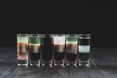 Küçük bardaklar, siyah bir masada içki içerler. 