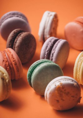 Mercan ya da turuncu arka planda tatlı, renkli bir makaron seti. Fransız geleneksel tatlısı