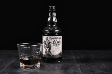 Yüzbaşı Morgan siyah arka planda rom bardağı ve şişe.