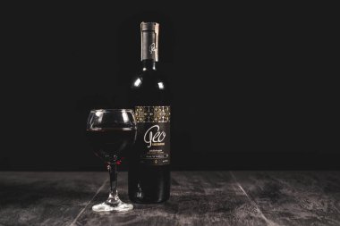Siyah arka planda bir bardak şarap ve şişe.