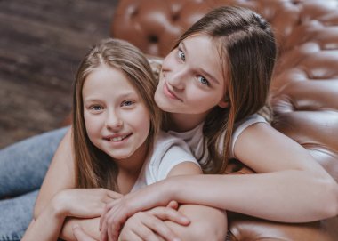 İki güzel kız kardeş portresi. Evdeki yatakta oturan güzel, neşeli kızlar.