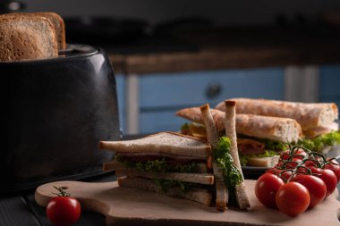 Taze ekmek takımı. Atıştırmalık Ciabatta, baget, domatesli sandviç ve mutfakta salata.