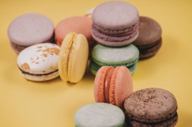 Sarı arka planda tatlı, renkli makarna seti. Fransız geleneksel tatlısı