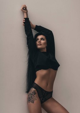Beyaz arka planda odada duran güzel, genç, baştan çıkarıcı bir kadın. İç çamaşırı ve spor ayakkabı giyen çekici, seksi bir manken. Güzel bir portre.